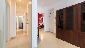 A hallway with a wooden door, a kitchen area with a red accent wall, and a dining area with chairs. - GuestHost - Large 160 sqm apartment, ideal for groups or families up to 6, located on the first floor of a building with an elevator (NOT for guests with disabilities).The property is located in a quiet area, yet fully served by all main amenities and we (Palermo)