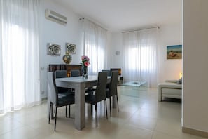 Un comedor con mesa y sillas, un sofá, una mesita de centro y un cuadro en la pared.