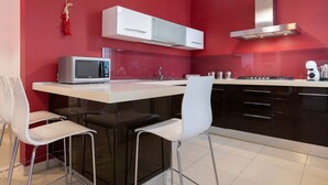 A modern kitchen with a red wall, white cabinets, a microwave, and two white chairs. - GuestHost - Large 160 sqm apartment, ideal for groups or families up to 6, located on the first floor of a building with an elevator (NOT for guests with disabilities).The property is located in a quiet area, yet fully served by all main amenities and we (Palermo)