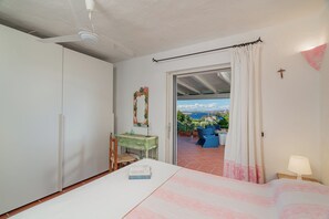A bedroom with a bed, a dresser, a mirror, and a view of the outdoors. - Villa Pitrizzina 8, Emma Villas (Sassari)