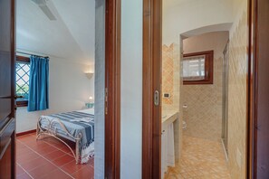 Ein Schlafzimmer mit Bett, Nachttisch und einem Fenster mit Vorhängen.