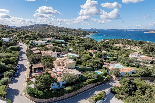 Ein Küstenwohngebiet mit Häusern, einer kurvenreichen Straße und Blick auf das Meer.