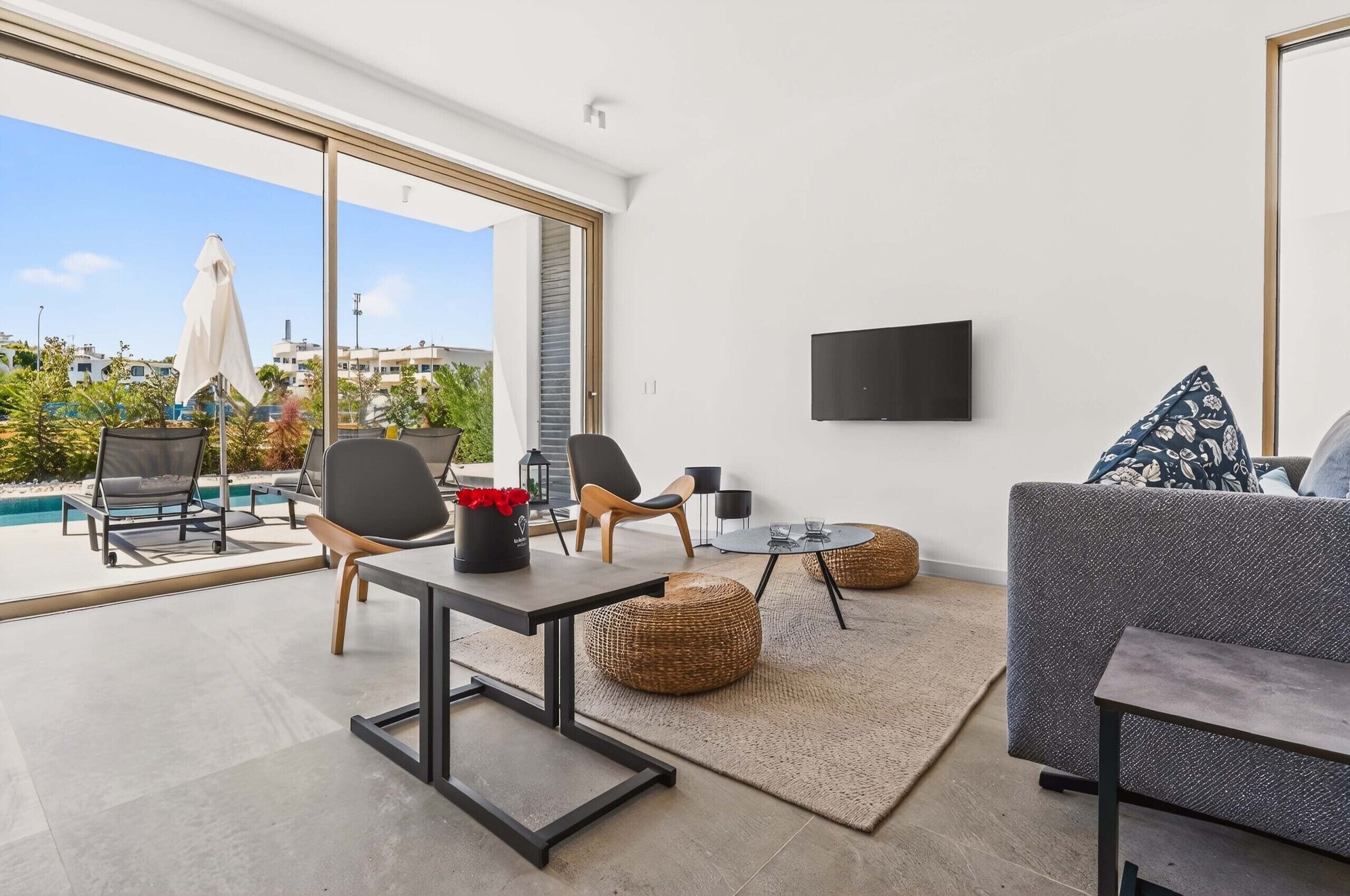 A modern living room with a pool view, a flat-screen TV, and comfortable seating.