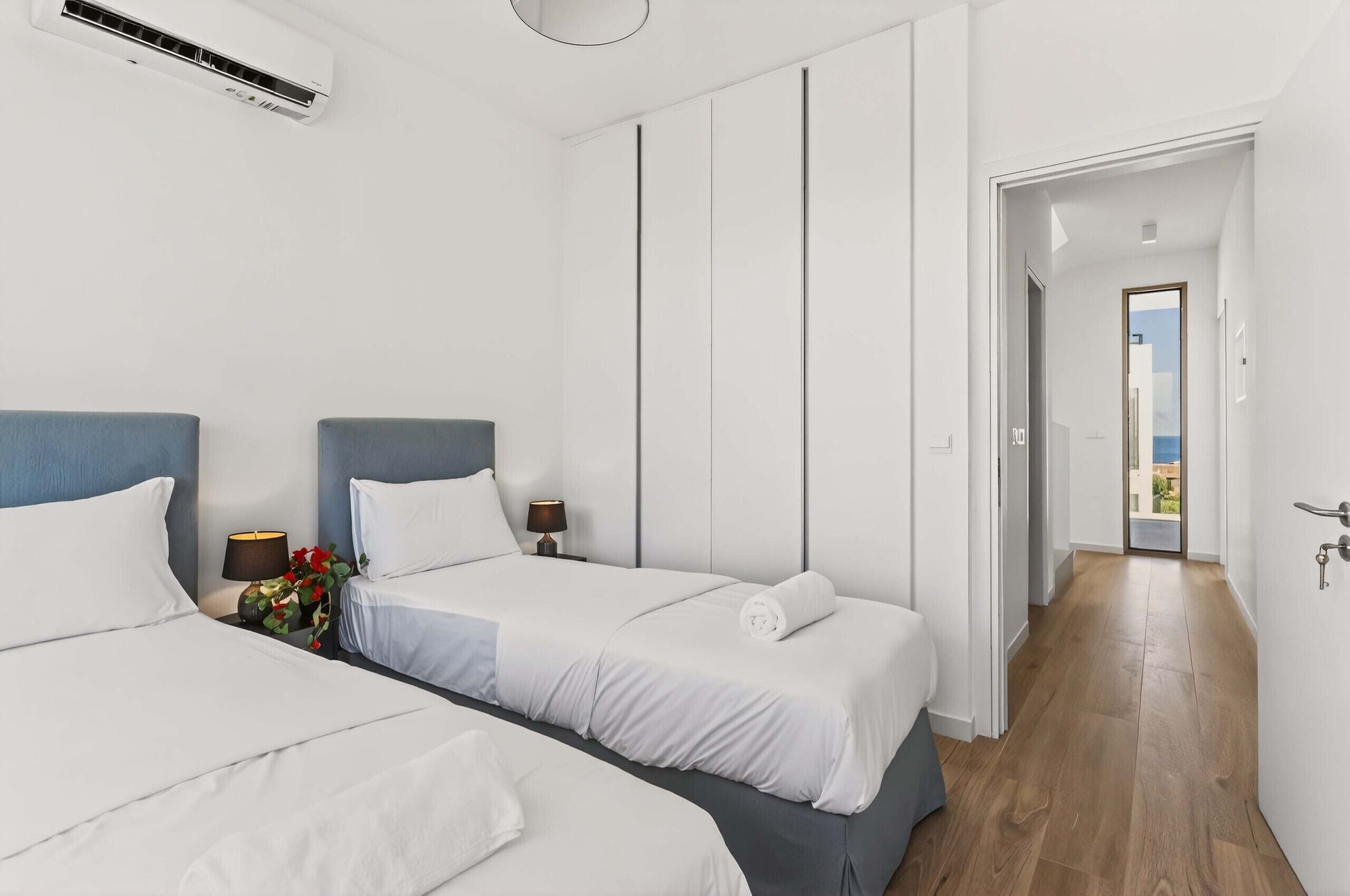 A hotel room with two beds, a hallway, and a door leading to a balcony.