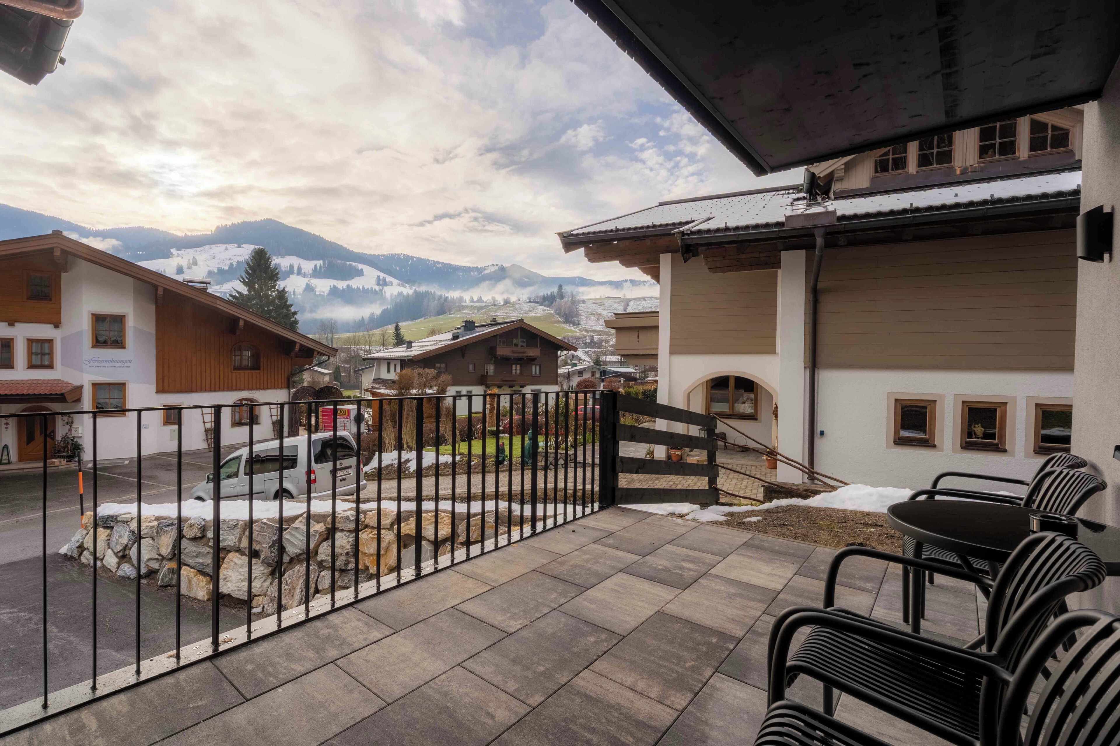 Una terraza con vistas a montañas, una verja y un edificio con garaje.