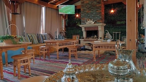 A cozy living room with a fireplace, wooden furniture, and a television mounted on the wall.