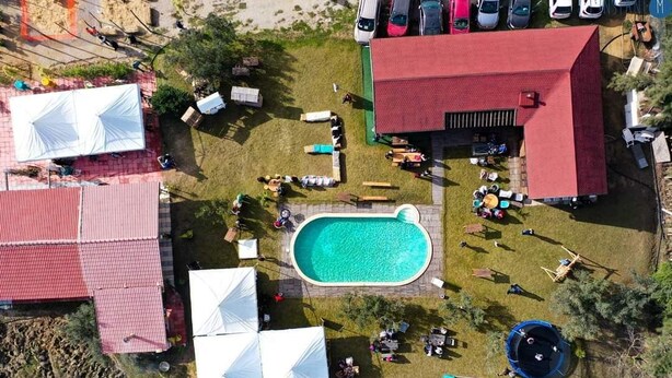 Vista aérea de una propiedad con piscina, varias carpas blancas y un edificio de techo rojo.