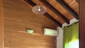 Un dormitorio con pared de madera, una cama, una lámpara colgante y una ventana con cortinas.