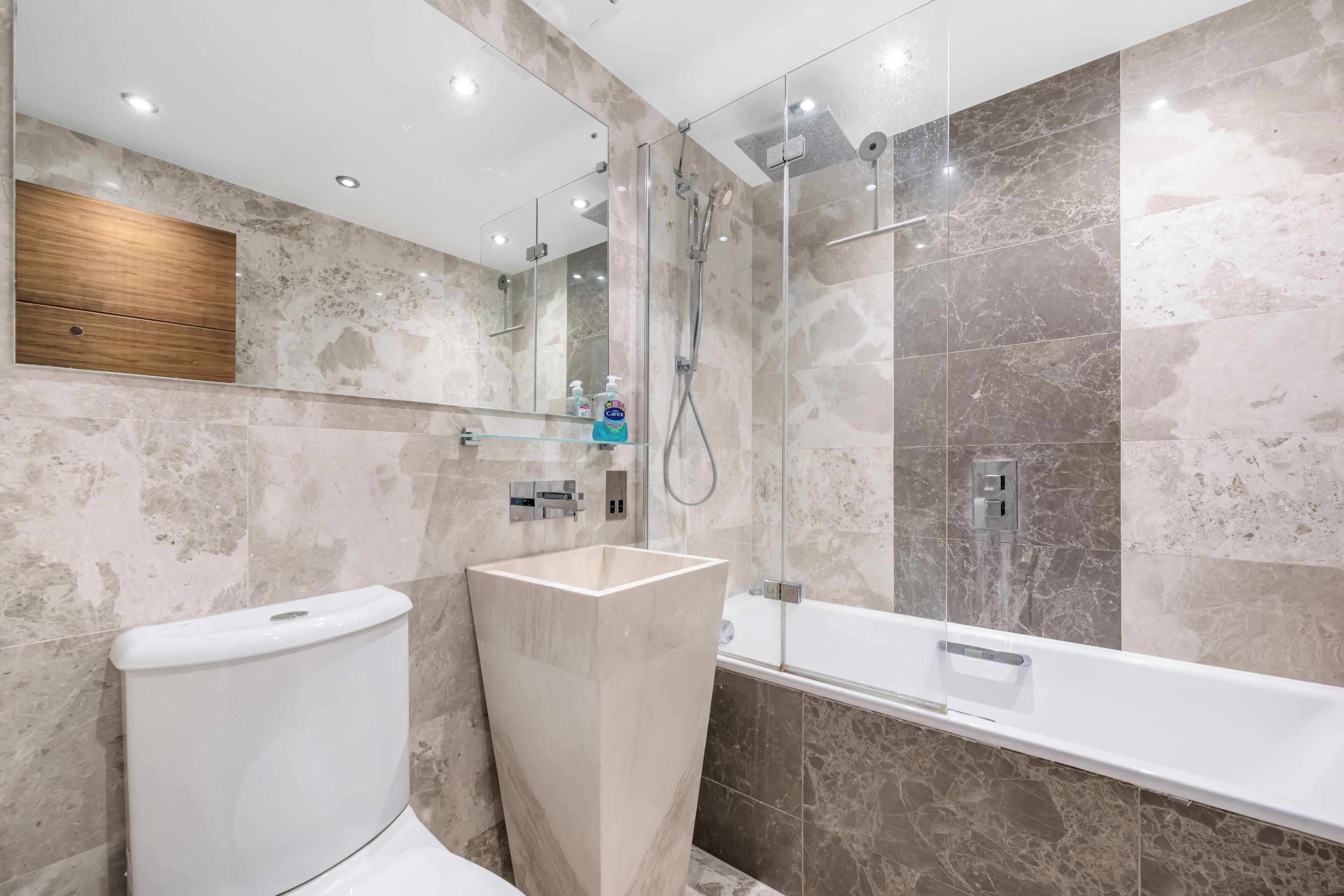 Ein modernes Badezimmer mit Toilette, einem großen rechteckigen Waschbecken, einer Duschkabine aus Glas und einer Badewanne.