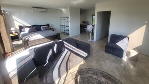 A modern hotel room with a large bed, two sofas, a small table, and a floor lamp. - Casa Pura Vista (Playa Hermosa)