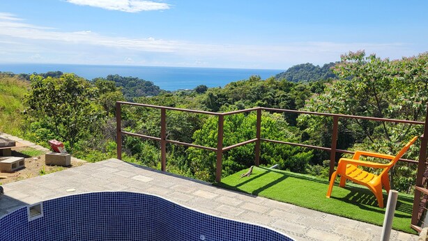 A swimming pool with blue mosaic tiles, surrounded by a stone deck and a metal railing. - Casa Pura Vista (Playa Hermosa)
