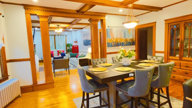 Un coin repas avec une table en bois, dressée pour quatre personnes, entourée de chaises rembourrées.
