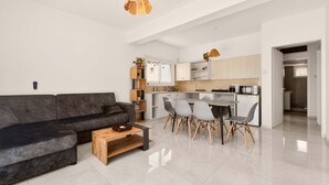Een moderne woonkamer met een bank, salontafel en een eetgedeelte met stoelen.