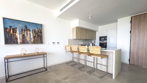 Una cocina moderna con barra, un cuadro de paisaje urbano y una consola decorada con objetos decorativos.