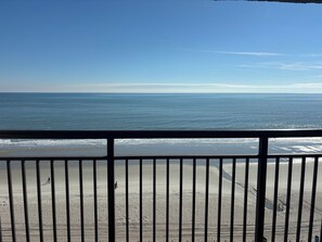 A beach view from a balcony with a railing, sandy beach, and ocean. - Oceanfront Paradise with Amazing Views (Myrtle Beach)