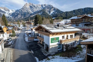 Un edificio con un letrero que dice 'KUCKLCK' en una zona montañosa con suelo cubierto de nieve y una carretera que atraviesa la escena.
