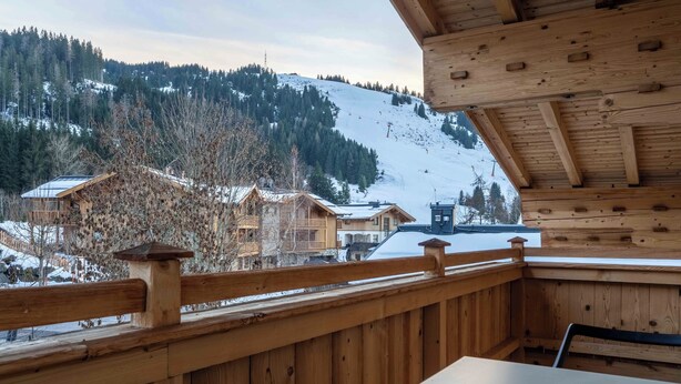 A wooden cabin with a balcony overlooking a snowy mountain.