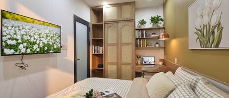 A bedroom with a bed, a desk, a bookshelf, and a television.