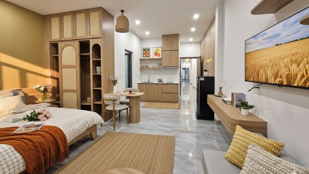Ein modernes Hotelzimmer mit einem großen Bett, einer Sitzecke mit einem kleinen Tisch, einer Küchenzeile und einem Essbereich.