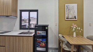Eine kompakte Küche mit Fenster, einem schwarzen Kühlschrank, einem Esstisch mit Stühlen und einer Vase mit Blumen.