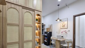 Ein modernes Interieur mit einem Holzschrank mit Lochblech, einem Essbereich mit Tisch und Stühlen sowie einem Kühlschrank.
