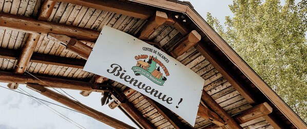 En träkonstruktion med en skylt som visar texten ”Centre de Vacances Camp Forester Saint-Luc-de-Bellechasse” och ”Välkommen!”.