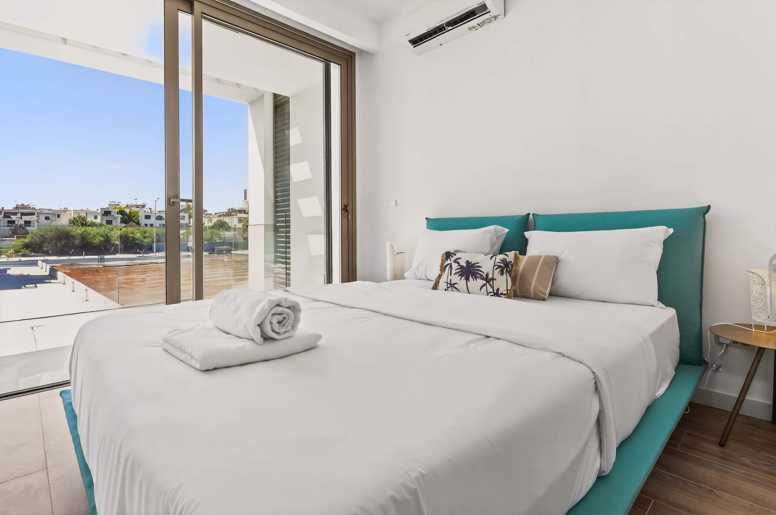 Ein Hotelzimmer mit einem großen Bett, Blick auf die Stadt und einem Balkon.