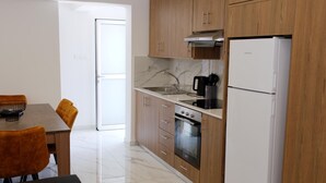 Una cocina moderna con armarios de madera, un horno de acero inoxidable, un refrigerador blanco y un comedor con mesa y sillas.