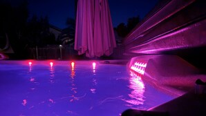 Une piscine dotée d’un éclairage violet et agrémentée d’un élément décoratif aquatique.