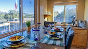 Un coin repas avec une table mise pour le repas, une fenêtre donnant sur l’extérieur et un drapeau posé sur le rebord de la fenêtre.