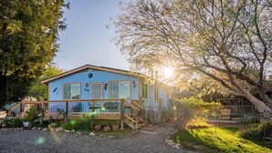 Une maison bleue avec une terrasse en bois et une allée gravillonnée.