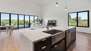 Una cucina moderna con un'isola grande, elettrodomestici integrati e ampie finestre che offrono vista sull'esterno.
