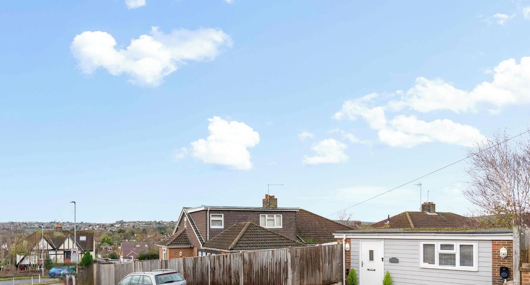 A residential area with houses, a wooden fence, and a clear sky.