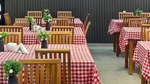 Ein Restaurant mit rot-weißen Karotischdecken, Holztischen und Blumentöpfen auf den Tischen.
