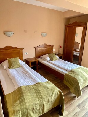 A room with two single beds, wooden headboards, a nightstand, a mirror, and a wall-mounted light fixture. - HOTEL LUCY STAR (Cluj-Napoca)