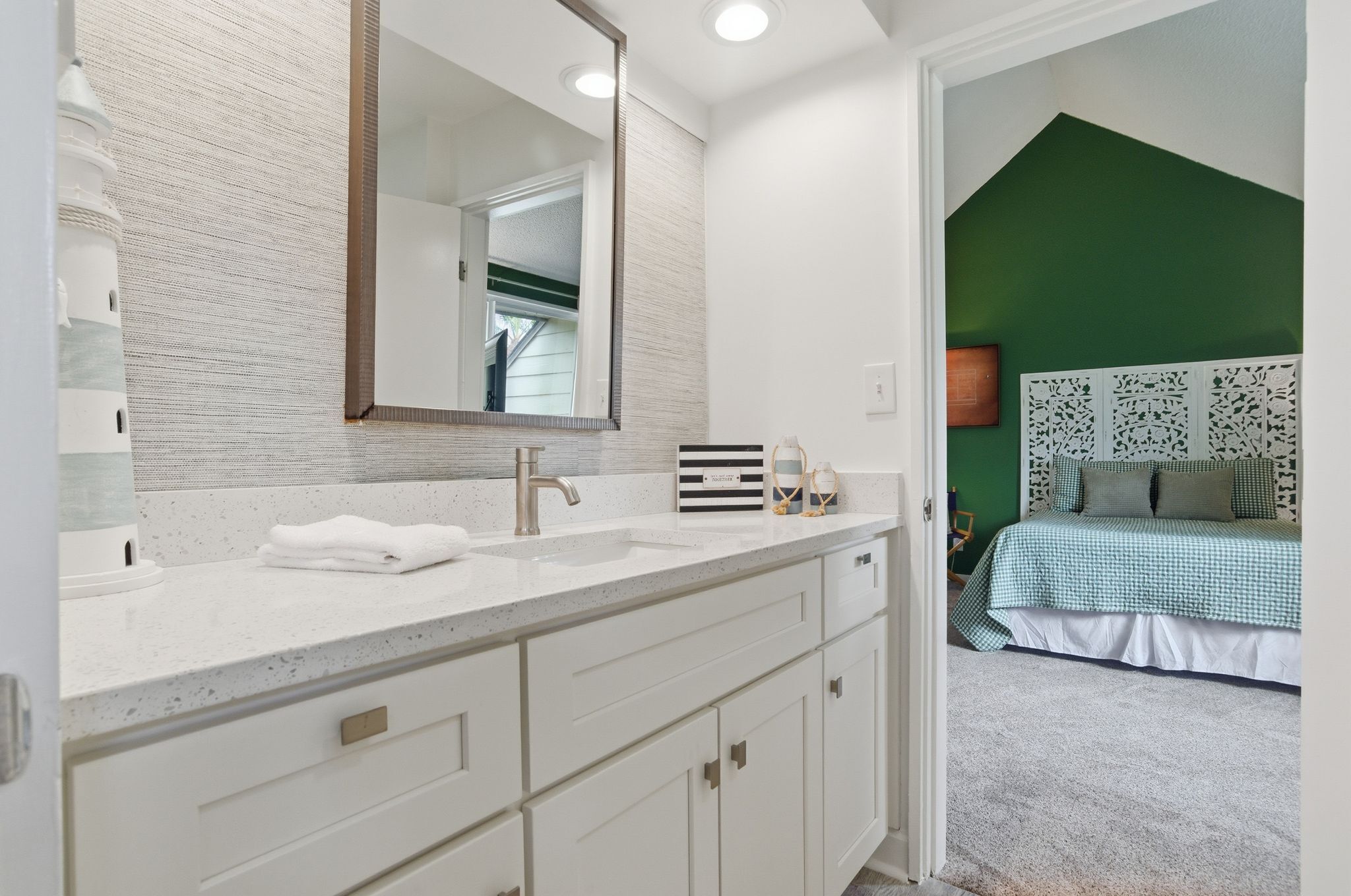 A bathroom with a large mirror, double sink, and white cabinetry.