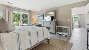 Un dormitorio con cama, cómoda, espejo y vistas al exterior.