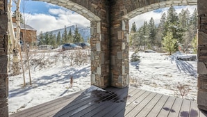 A stone archway leading to a snowy outdoor area with a wooden deck. - New! Snowcreek Luxury Retreat w Mountain Views 641 (Mammoth Lakes)