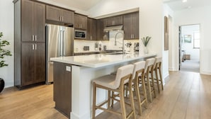 A modern kitchen with dark wood cabinets, stainless steel appliances, and a central island with bar stools. - New! Snowcreek Luxury Retreat w Mountain Views 641 (Mammoth Lakes)