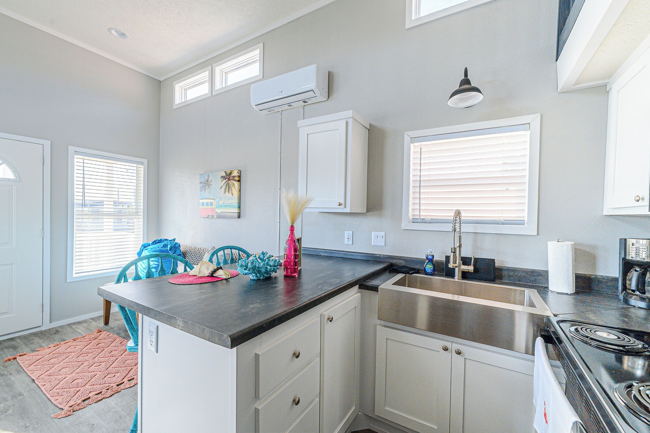 A modern kitchen with white cabinets, a black countertop, and a stainless steel sink.