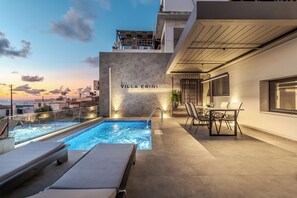 A rooftop pool area with lounge chairs, a dining table, and a sign reading "Villa Erini." - Villa Erini (Hersonissos)