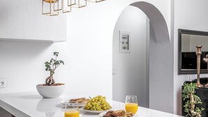 Una cocina moderna con una isla blanca, lámparas colgantes y una planta en maceta.