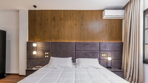Un dormitorio moderno con una cama grande, pared de paneles de madera y lámparas de noche.