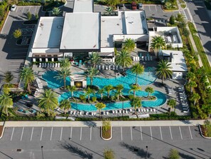 An aerial view of a hotel with a large swimming pool surrounded by palm trees and lounge chairs. - New Luxury 5BR • Walk to SeaWorld (Orlando)
