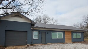 A modern single-story house with a dark exterior, a garage, and two windows with blinds. - Serene Modern Space on a Pecan Grove near Historic Downtown Abbeville (Abbeville)