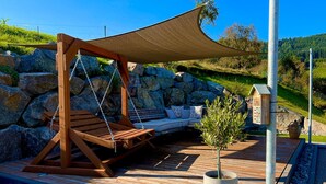 A wooden swing chair under a shade sail, a seating area with cushions, and a potted plant on a wooden deck. - Apartment “Black Forest Brandenkopfblick” with Terrace, Garden and Wi-Fi (Zell)