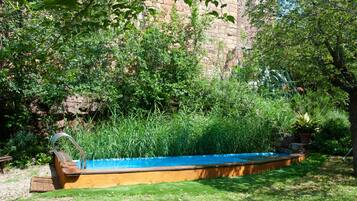 A swimming pool surrounded by lush greenery and a stone wall.