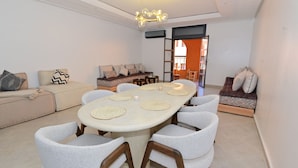 Ein modernes Wohnzimmer mit einem großen ovalen Tisch, mehreren Sofas und einer Kronleuchter.