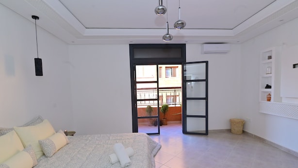 Ein modernes Schlafzimmer mit einem großen Bett, einem kleinen Nachttisch, einem Kleiderschrank und einem Balkon mit Aussicht.