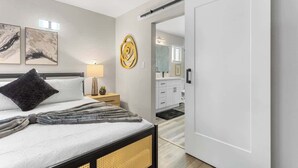 A bedroom with a bed, bedside table, lamp, and artwork. - The Big Group Paradise: Pool, Games, & More! (North Las Vegas)